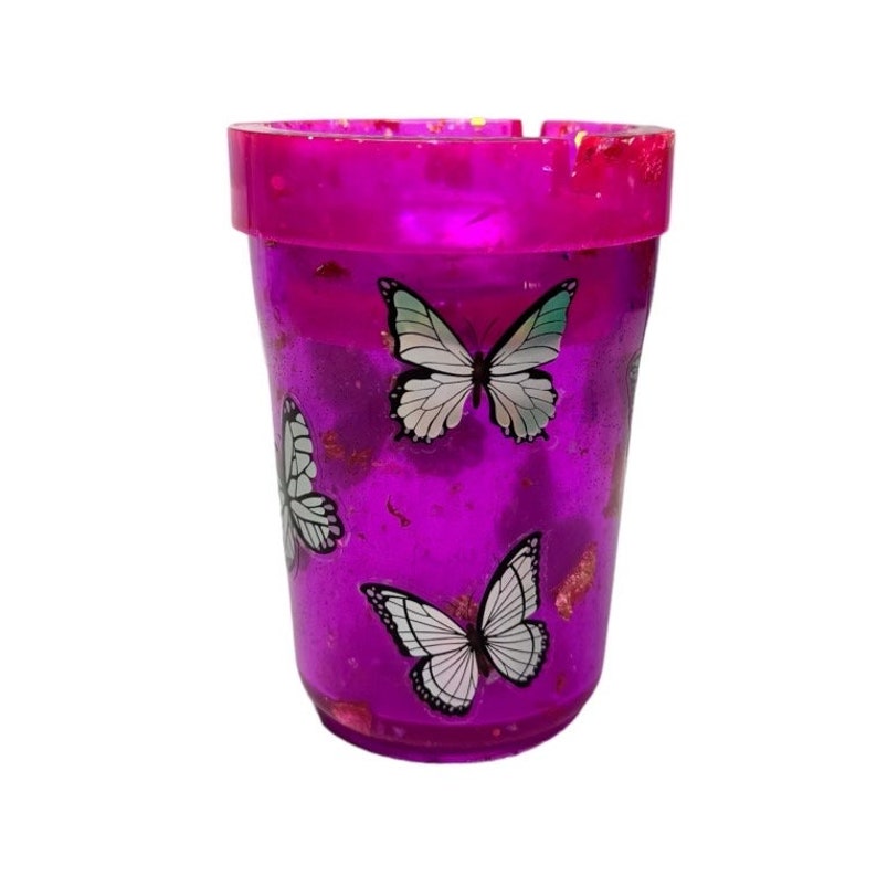 May include: A purple glass ashtray with a glittery finish and a design of white butterflies.