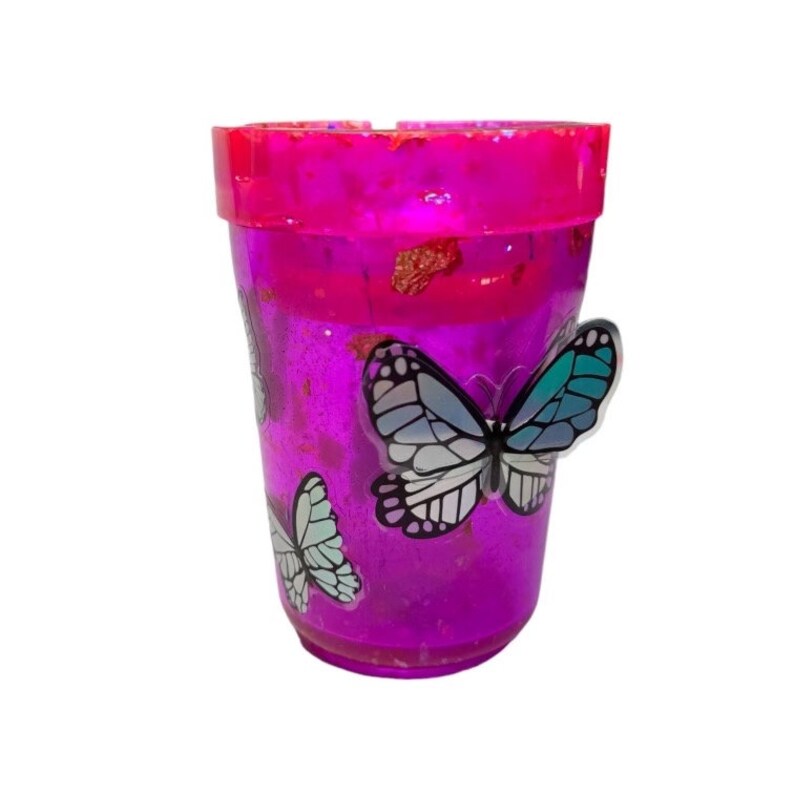 May include: A purple plastic cup with glitter and butterfly decals. The cup has a wide rim and a rounded bottom.
