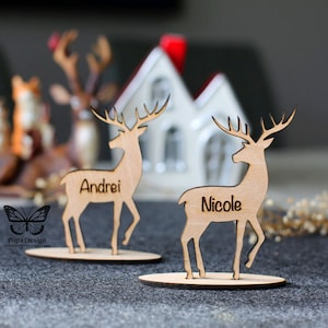 Tovaglie personalizzate con renne natalizie, nomi incisi in legno sul supporto. Idea per decorazioni per la tavola festiva con biglietti rustici personalizzati per posti a sedere