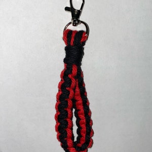 Peut inclure: Un porte-clés tressé noir et rouge avec un fermoir en métal argenté.