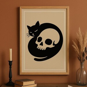 May include: A framed art print featuring a black cat curled around a white skull. The cat and skull are set against a beige background, framed in a light wood. The artwork has a minimalist, gothic aesthetic.