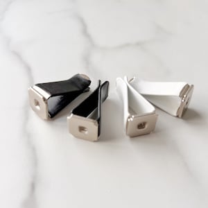 Könnte beinhalten: Drei Auto-Lufterfrischer-Clips, zwei weiße und ein schwarzer. Die Clips sind aus Kunststoff und haben einen Metallclip, um den Lufterfrischer zu halten.