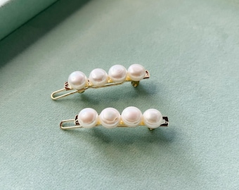 Puede incluir: Dos pinzas para el pelo doradas con detalles de perlas blancas. Cada pinza tiene cinco perlas.