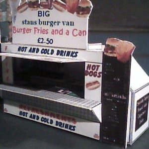 May include: A cardboard model of a food stand with a sign that reads "BIG stans burger van Burger Fries and a Can £2.50 HOT AND COLD DRINKS". The stand has a menu board with the words "HOT DOGS" and a sign that reads "REFRESHMENTS HOT AND COLD DRINKS".