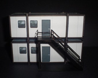 May include: A white two-story building with a black metal staircase leading to the second floor. The building has windows on each floor and a door on the second floor.
