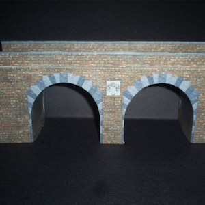 Puede incluir: Un modelo de puente de ladrillo de doble arco con dos aberturas. El puente está hecho de ladrillo marrón con arcos de piedra gris. El puente es un accesorio de modelismo ferroviario.