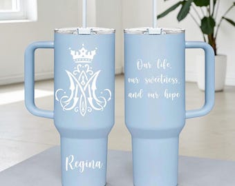 May include: Two light blue insulated tumblers with handles and straws. One tumbler features a white crown and monogram design with the name "Regina." The other has the text "Our life, our sweetness, and our hope."