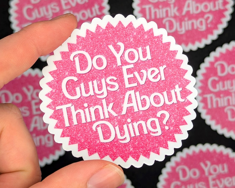 K&ouml;nnte beinhalten: Runder rosa Aufkleber mit einem wei&szlig;en Sternendesign und dem Text "Do You Guys Ever Think About Dying?" in wei&szlig;en Buchstaben.