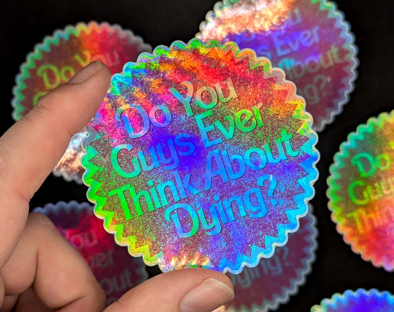 K&ouml;nnte beinhalten: Ein holografischer Aufkleber mit dem Text "Do You Guys Ever Think About Dying?" in einem Regenbogen-Farbschema.