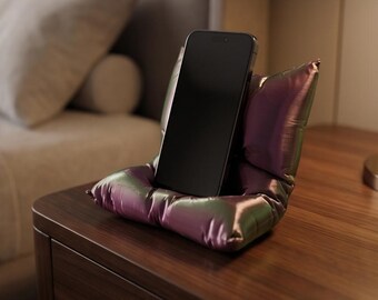 Suporte/apoio para celular exclusivo, impresso em 3D, em formato de "almofada fofa", nas cores rosa e verde.