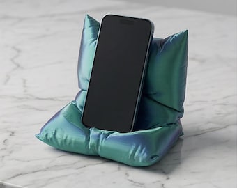 Suporte/base para celular exclusivo, impresso em 3D, em formato de "almofada fofa", nas cores verde e preta.
