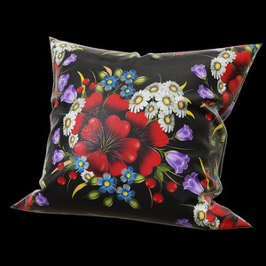 Puede incluir: Almohada negra con un patrón floral con flores rojas, blancas, azules y verdes.