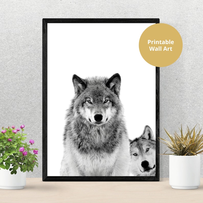 May include: Black and white printable wall art featuring two wolves. The wolf in the foreground is looking directly at the viewer, while the wolf in the background is looking to the side. The text "Printable Wall Art" is in the top right corner of the image.