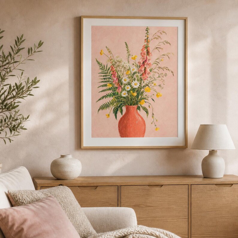 Peut inclure: Une impression d'art murale encadr&eacute;e repr&eacute;sentant une illustration botanique d'un bouquet de fleurs sauvages dans un vase corail. La composition comprend des digitales roses, des marguerites blanches, des boutons d'or et des foug&egrave;res vertes.
