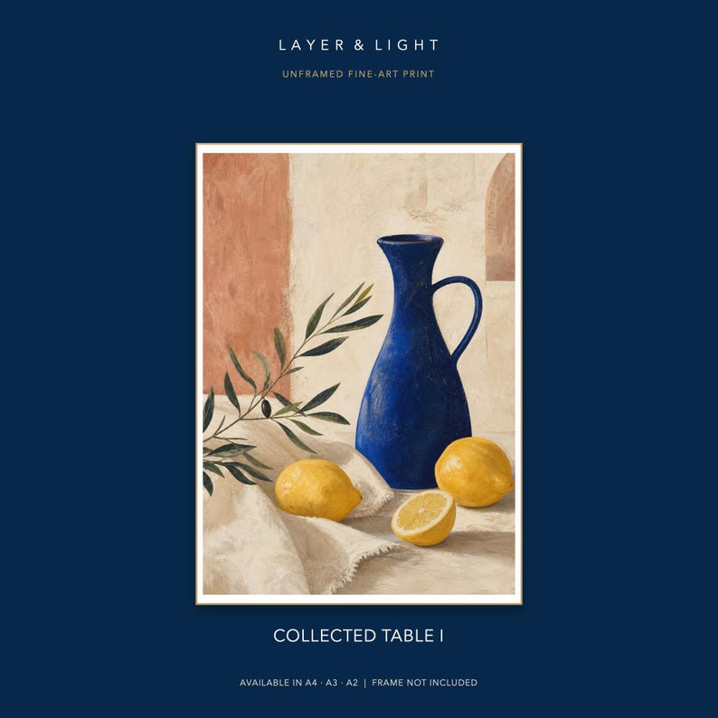K&ouml;nnte beinhalten: Ein Kunstdruck mit dem Titel LAYER & LIGHT COLLECTED TABLE I, der einen blauen Krug, drei gelbe Zitronen und einen Olivenzweig auf einem wei&szlig;en Tuch zeigt. Der Hintergrund zeigt eine strukturierte Wand in Creme- und Terrakottat&ouml;nen. Ungerahmter Druck.