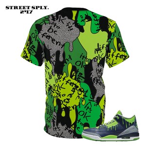 Puede incluir: Una camiseta gr&aacute;fica verde, negra y amarilla con el texto "it's ok to be different" impreso en ella. Un par de zapatillas verdes y azules con un dise&ntilde;o de goteo verde.