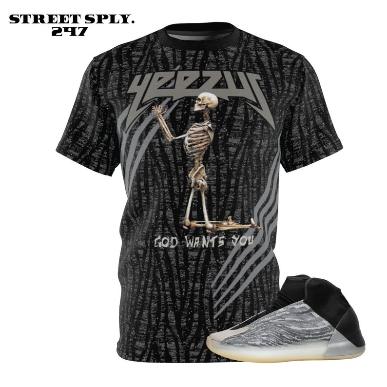 May include: A black and grey t-shirt featuring a skeleton graphic and the text "YEEZY" and "GOD WANTS YOU". The t-shirt is paired with a grey and white sneaker.
