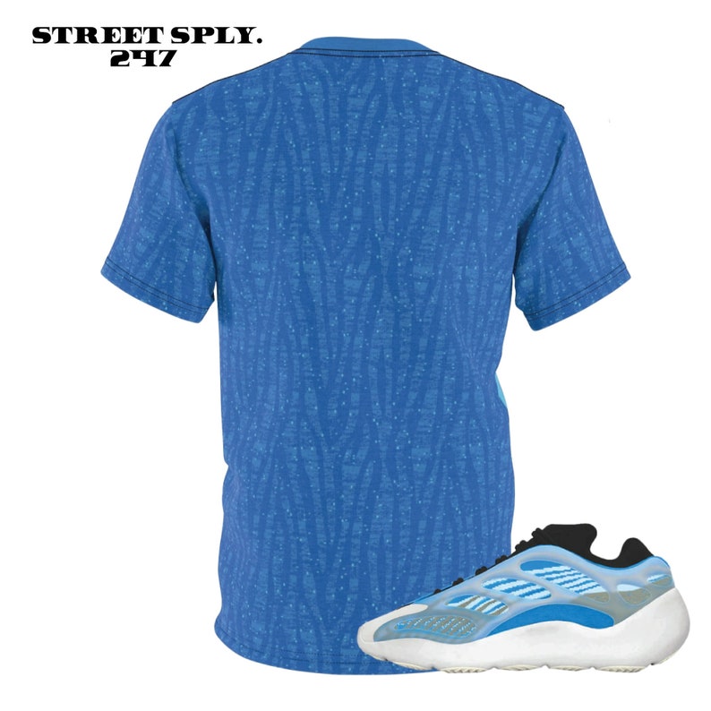 Puede incluir: Una camiseta azul y blanca con estampado y un par de zapatillas blancas y azules. Las zapatillas tienen un acento negro en la parte posterior.