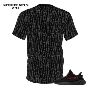 Puede incluir: Camiseta negra y gris con estampado y una zapatilla negra y roja con el texto "SPLY-350" en el lateral.
