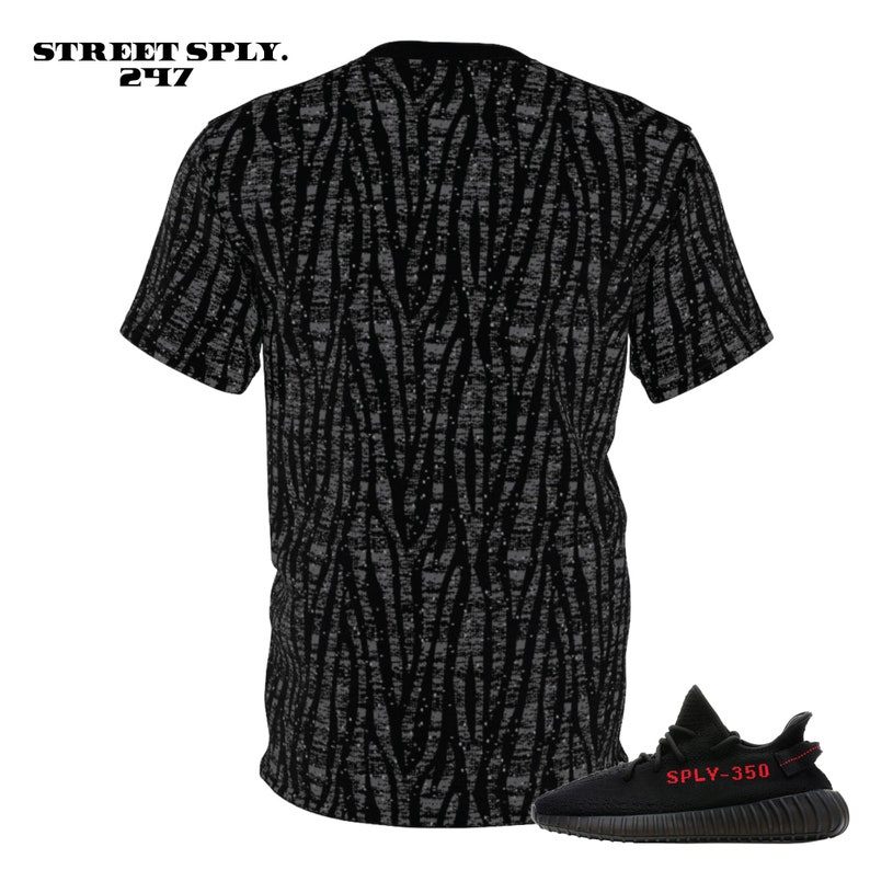 Puede incluir: Camiseta negra y gris con estampado y una zapatilla negra y roja con el texto "SPLY-350" en el lateral.