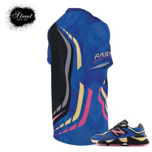 Puede incluir: Una camiseta azul y negra con estampado y la palabra "FAST" en la manga, combinada con una zapatilla New Balance azul, negra, amarilla y rosa.