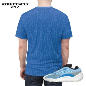 Puede incluir: Una camiseta azul y blanca con estampado y un par de zapatillas azules y blancas. La camiseta tiene un peque&ntilde;o logotipo que dice "STREET SPLY. 247".