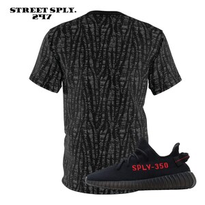 May include: Black and grey patterned t-shirt with a black and red sneaker with the text "SPLY-350" on the side.
