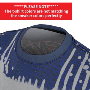 Puede incluir: Primer plano de una camiseta azul marino con un dise&ntilde;o de salpicaduras de pintura blanca y azul. El texto "PLEASE NOTE" se muestra en rojo sobre la imagen. El texto dice "Los colores de la camiseta no coinciden perfectamente con los colores de las zapatillas."