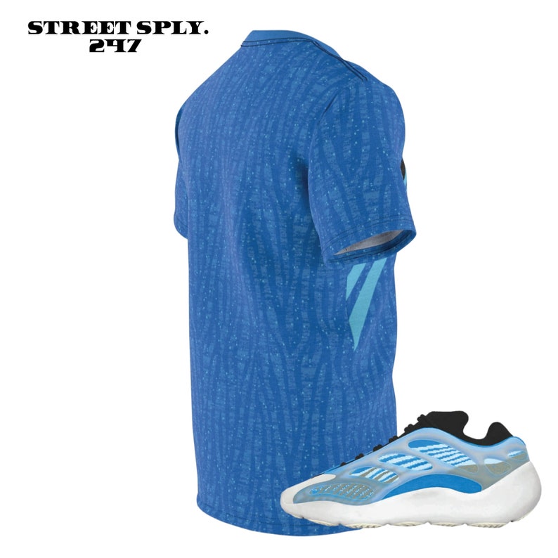 Puede incluir: Una camiseta de manga corta azul y blanca con estampado y una zapatilla azul y blanca. La camiseta tiene una raya azul y blanca en la manga. La zapatilla tiene una suela blanca y una parte superior azul y blanca.