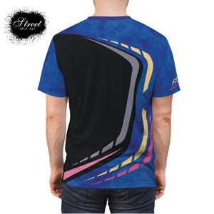 Puede incluir: Una camiseta gr&aacute;fica azul, amarilla, rosa y gris con un dise&ntilde;o geom&eacute;trico. La camiseta tiene un patr&oacute;n de malla negra en la espalda.