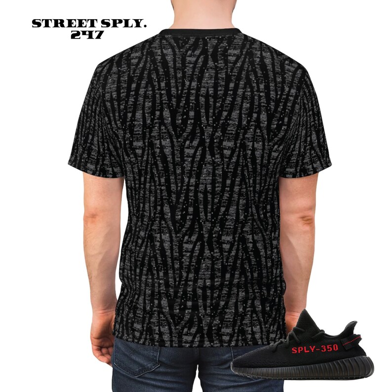 Puede incluir: Camiseta negra y gris con estampado de cebra y una zapatilla negra y roja con el texto "SPLY-350" en el lateral.