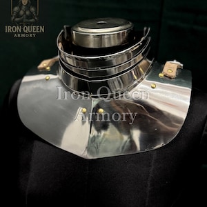 Può includere: Un gorgiera in acciaio lucido, parte di un'armatura medievale, con una protezione per il collo a strati e una sezione inferiore svasata. La gorgiera è rivettata e presenta cinghie in pelle. Il logo Iron Queen Armory è visibile.