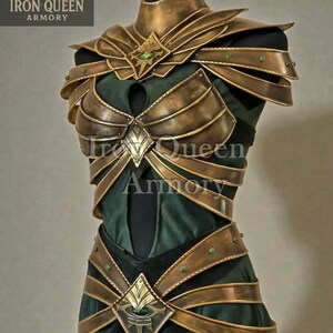 May include: A gold-colored breastplate and shoulder armor set with green accents, displayed on a mannequin. The armor is layered over a dark green fabric. The Iron Queen Armory logo is visible in the upper left corner.