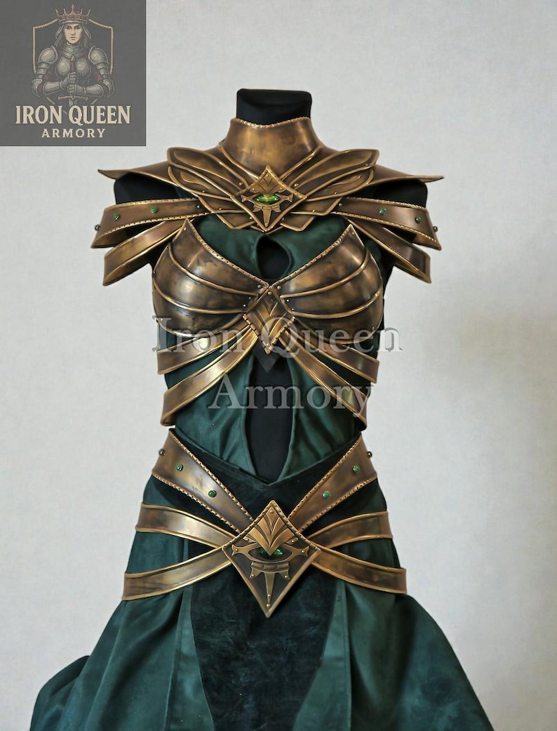 May include: A detailed shot of a fantasy costume. The armor is a metallic gold color with green accents and gemstones. The costume is displayed on a mannequin and features a breastplate, shoulder armor, and a belt. The dress underneath is dark green.