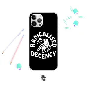 May include: Black phone case featuring the text "RADICALISED BY BASIC DECENCY" in white, with a bird illustration. Pencils, paper clips, and an eraser are arranged around the case. The case is for a smartphone.