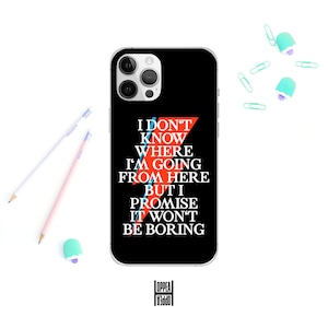 May include: Black phone case with the text "I DON'T KNOW WHERE I'M GOING FROM HERE BUT I PROMISE IT WON'T BE BORING" in white, red, and blue. The case has a clear border and a camera cutout. Pencils, paper clips, and an eraser are scattered around the case.