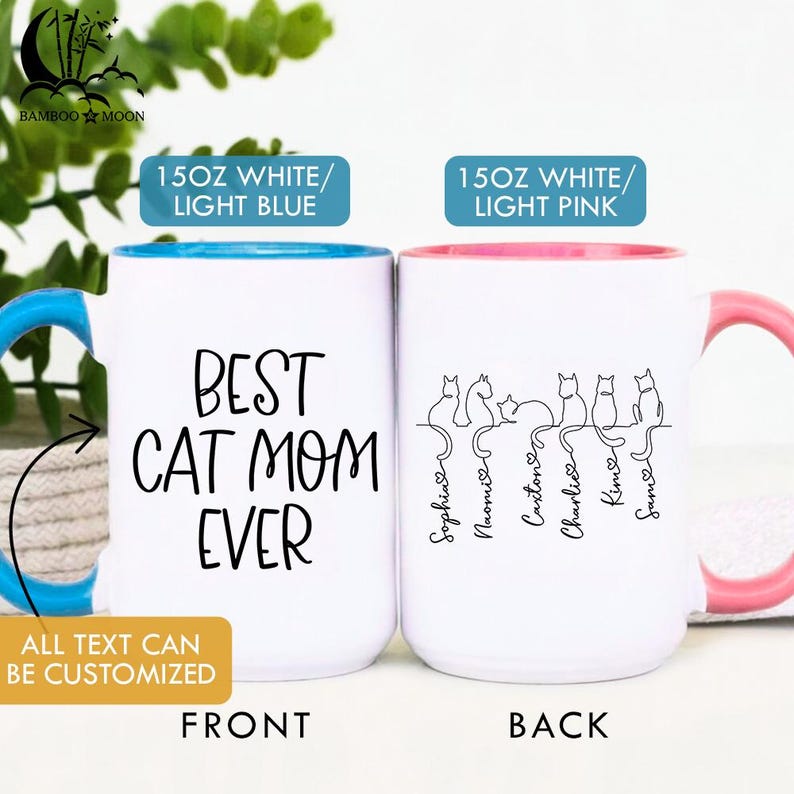 May include: Two white ceramic mugs with black text and cat illustrations. One mug has a blue interior and handle, the other has a pink interior and handle. The front mug reads "BEST CAT MOM EVER". The back mug has cat silhouettes and names.