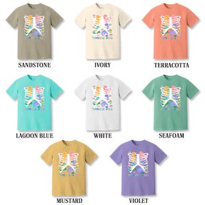 Pu&ograve; includere: Un set di dieci t-shirt con una grafica colorata di una gabbia toracica con dinosauri al suo interno. Le t-shirt sono disponibili in dieci colori diversi: arenaria, avorio, terracotta, blu laguna, bianco, spuma di mare, senape, viola, nero e grigio melange. Il testo "Thoracic Park" &egrave; stampato sulle t-shirt.