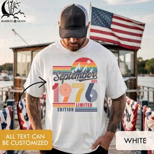 May include: A white short-sleeve t-shirt featuring a graphic with the text September 1976 Limited Edition. The design includes a mountain landscape, a sun, and horizontal stripes in red, orange, yellow, blue, and purple colors.