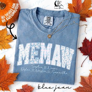 Könnte beinhalten: Ein blaues kurzärmeliges T-Shirt mit Vintage-Waschung. Das Wort MEMAW ist in großen Blockbuchstaben mit einem hellblauen und weißen Blumen- und Vichy-Muster aufgedruckt. Darunter stehen die Namen Sophia, Naomi, Dylan, Dayton und Samantha.