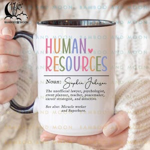 May include: White ceramic mug with a black interior and handle, featuring the words "HUMAN RESOURCES" in colorful letters. The mug includes a definition and a list of related roles, making it a humorous gift for HR professionals.