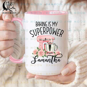 May include: White ceramic mug with a pink interior and handle. The mug features the text "Baking is my Superpower" with a pink stand mixer graphic and the name "Samantha". Floral accents surround the mixer.