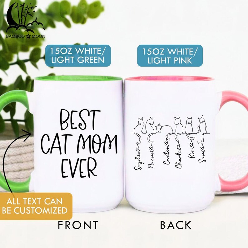 May include: Two white ceramic mugs with colorful handles and rims. One mug has a green handle and rim with "Best Cat Mom Ever" text. The other has a pink handle and rim with cat silhouettes and names.