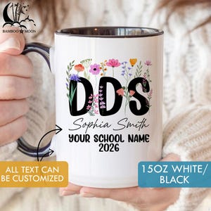 May include: White ceramic mug with a black interior and handle, featuring the letters "DDS" surrounded by colorful flowers. The mug includes the name "Sophia Smith", "YOUR SCHOOL NAME", and the year "2026". The mug is 15oz.