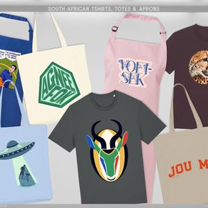 May include: A selection of South African themed t-shirts, totes, and aprons. Features a blue apron with a comic strip, a cream tote bag with a green geometric design, a grey t-shirt with an antelope graphic, and a light blue tote bag with a UFO design.