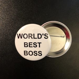 May include: White button with the text "WORLD'S BEST BOSS" in black lettering.