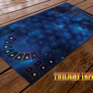 Puede incluir: Un tapete de juego rectangular con temática espacial, con un diseño de galaxia azul oscuro con estrellas y formas hexagonales. El tapete incluye áreas numeradas y espacios para cartas, con el texto "TWILIGHT IMPERIUM" en dorado.