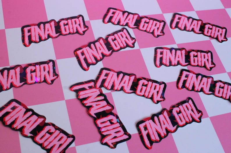 Pu&ograve; includere: Una collezione di toppe rosa e nere "FINAL GIRL" sparse su una superficie a scacchi rosa e bianca. Le toppe hanno un carattere audace e stilizzato con un contorno nero e un riempimento rosa.
