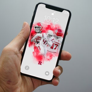 May include: A smartphone displaying a lock screen with a red and white football wallpaper. The wallpaper features three football players wearing red helmets and white jerseys with the word "TIGERS" on the front. The time on the screen is 10:12 and the date is Wednesday, July 6.