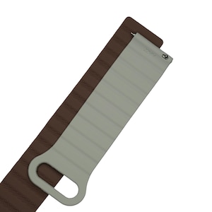 Könnte beinhalten: Ein braunes Lederuhrenarmband mit einer strukturierten Oberfläche und horizontalen Ziernähten. Daran befestigt ist ein hellgraues Silikon-Uhrenarmbandelement mit rechteckiger Form, horizontalen Rillen und einer Aussparung am Ende.
